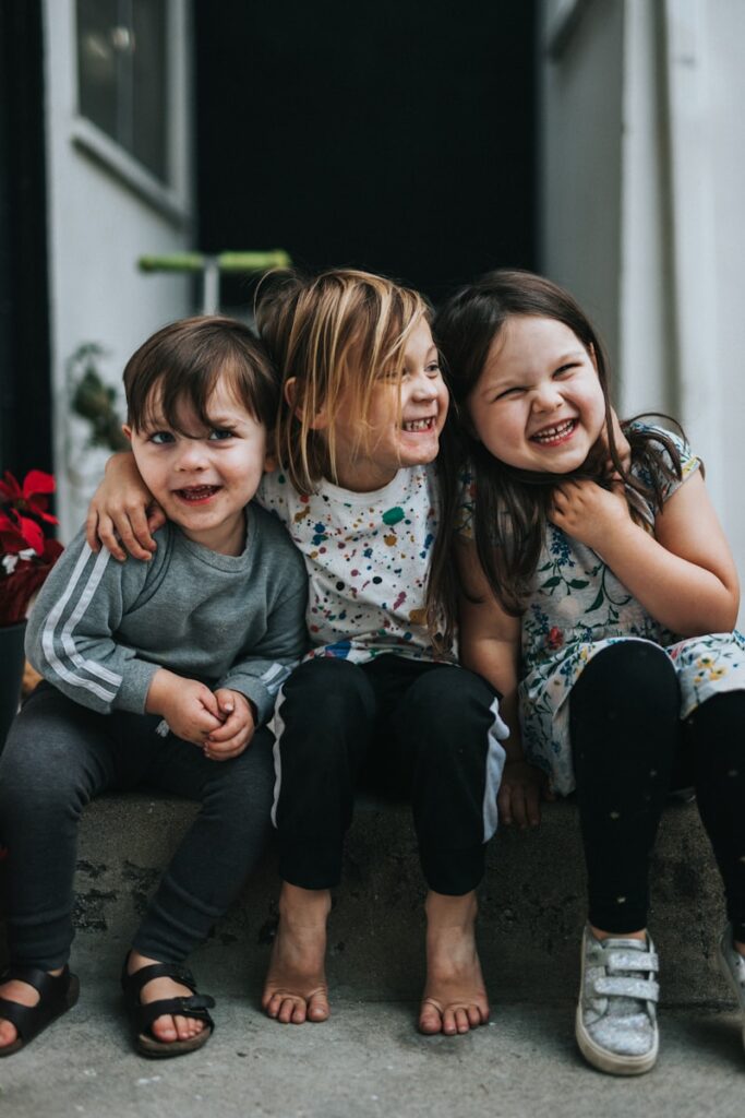3 kids smiling while sitting on step